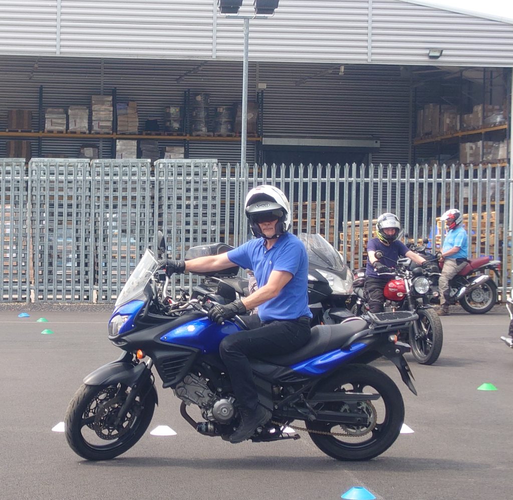 Blue motorcycle making slow turn, with rider looking towards turn